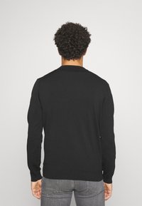 Schwarzer Pullover mit langen Ärmeln und Rundhalsausschnitt, weichem Material, geradem Schnitt und gerippten Bündchen; von hinten gezeigt.