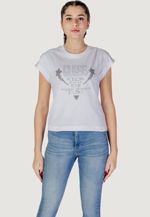 Vit kortärmad t-shirt med tryckt silvertext "GUESS FOLLOW YOUR DESTINY" och stjärngrafik. Mjuk bomullsmaterial, avslappnad passform.