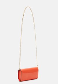 Bolso bandolera de charol rojo con forma rectangular, una correa de cadena dorada y textura lisa y brillante.