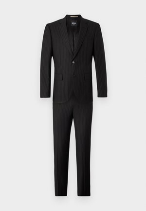 Completo a righe sottili nero realizzato in tessuto liscio. Giacca monopetto con rever a punte, due bottoni e pantaloni dritti coordinati.