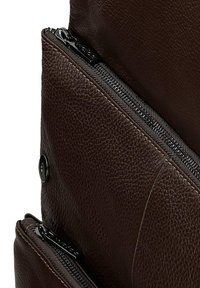 Bruine leren tas met een gestructureerd oppervlak, meerdere ritsen en een drukknoopsluiting. Het ontwerp benadrukt zichtbare stiksels en elegante hardware.