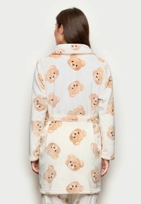 Accappatoio in pile con stampa di orsetti teddy su fondo crema, in tonalità marrone chiaro, dotato di cintura in vita e collo a scialle.