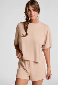 Beige bijpassende set bestaande uit een loszittend, kortermig shirt en shorts met elastische tailleband, gemaakt van zachte, lichtgewicht stof.