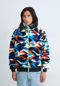 Fleecejacke mit einem mehrfarbigen abstrakten Muster in Blau, Rot, Schwarz und Grün. Voller Reißverschluss, hoher Kragen und elastische Bündchen.