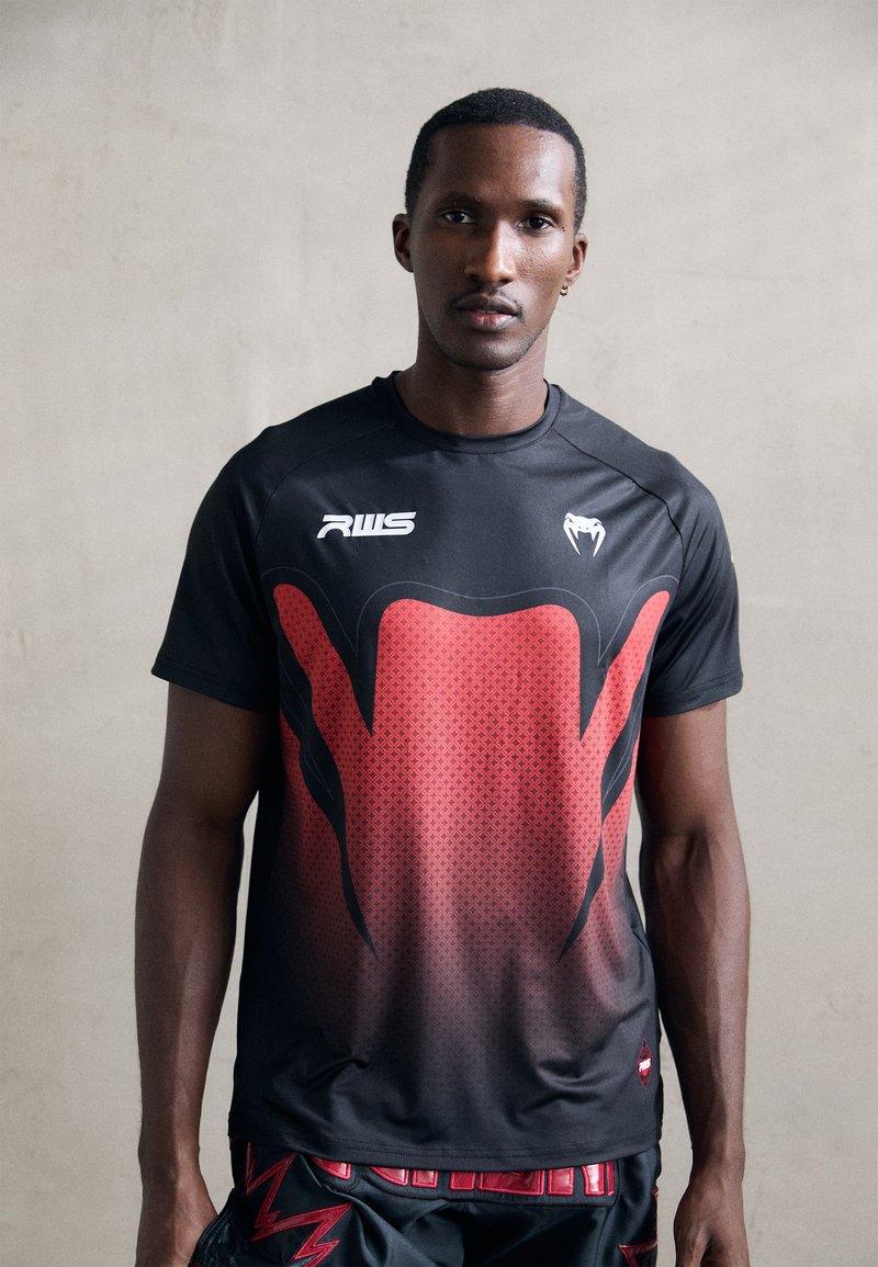 Schwarzes sportliches T-Shirt mit rotem Farbverlauf und gemusterter Gestaltung, ausgestattet mit Rundhalsausschnitt und kurzen Ärmeln. Logo auf der linken Brust.