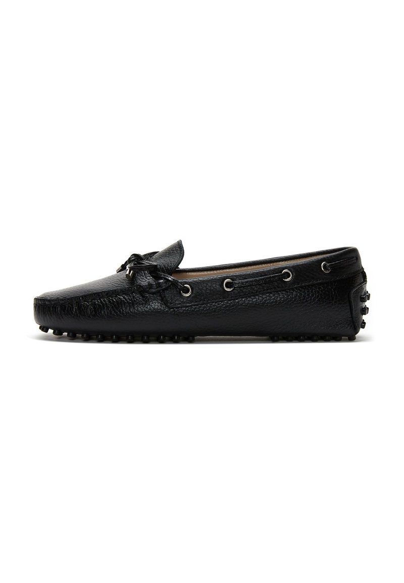 Mocasines planos de cuero negro con punta redonda, detalle decorativo de lazo, ojetes plateados y suela de goma con clavos para mayor agarre.