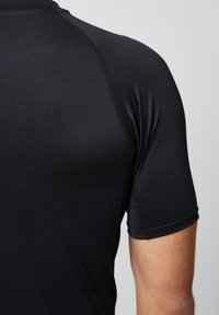 Zwart, sportshirt met korte mouwen, gemaakt van gladde, rekbare stof met subtiele textuur en versterkte stiksels op de schouders.
