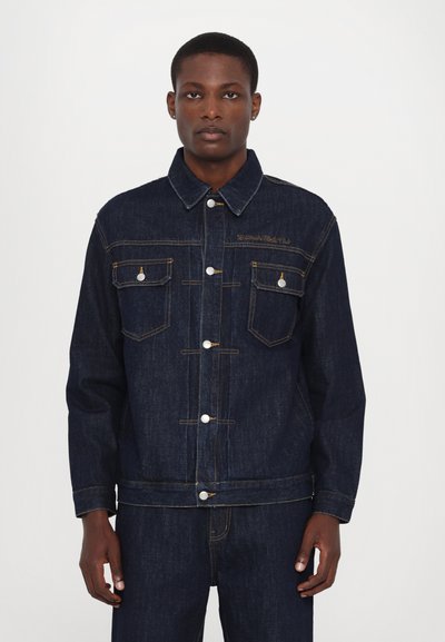 Jachetă din denim de culoare albastru închis, cu închideri cu butoane argintii, două buzunare pe piept și cusături în contrast. Prezintă un guler clasic și o croială lejeră.