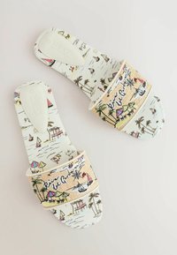 Sandales blanches à enfiler avec des illustrations colorées sur le thème de la plage et le texte « Riviera di Garda » sur de larges brides en tissu.