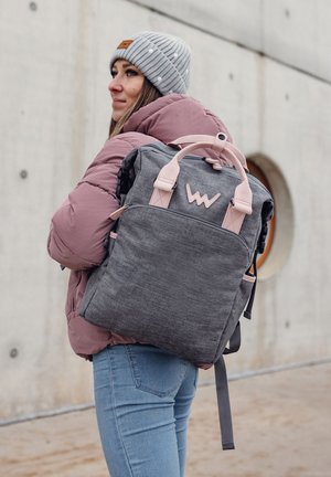 Grauer Rucksack aus Stoff mit rosa Akzenten und einem Logo, ausgestattet mit zwei oberen Griffen, verstellbaren Schultergurten und Außenfächern.