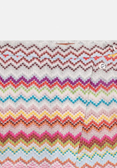 Tissu tricoté en zigzag multicolore avec des rangées horizontales dans des nuances de rouge, violet, bleu, vert, jaune et rose sur un fond clair.