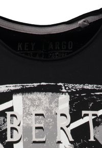 Czarna koszulka z dekoltem, z wyblakłym białym i szarym tekstem graficznym „BERT” oraz wewnętrzną metką „KEY LARGO”. 