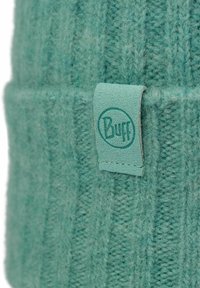 Teal knit beanie with a ribbed texture and a folded cuff. Features a matching leather logo patch. Soft, wool-like material.