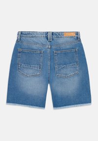 Denim kratke hlače v svetlo modri barvi, z raztrgano šivanko, dvema zadnjima žepoma in usnjeno nalepko nad pasom. Gladka tekstura.