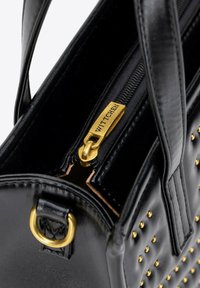 Černá kožená kabelka s nýtky ve zlaté barvě, zlatým jezdcem zipu s vyrytým nápisem "WITTCHEN" a dvojitými uchy pro nošení.