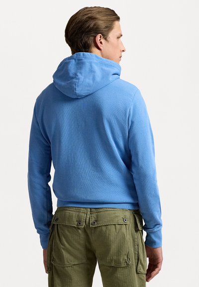 Lys blå hoodie med en kængurulomme, ribbede manchetter og kant. Kombineret med grønne cargo bukser med flere lommer og trykknaplukninger.