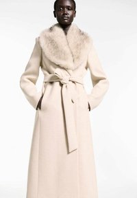Wrap coat in light beige fabric, featuring a faux fur collar, long sleeves, and a tied belt at the waist; smooth texture and floor-length design.