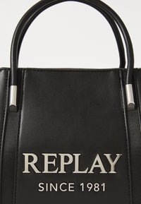 Zwarte leren handtas met twee korte handvaten. Bevat een geperst zilveren "REPLAY" logo en "SINCE 1981" aan de voorkant. Geëmbosserde afwerking.