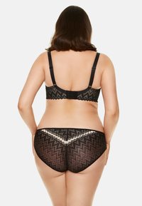 Czarny komplet bielizny koronkowej z wzorem zygzaków, regulowanymi ramiączkami oraz falbaniastymi akcentami na biustonoszu i pasujących majtkach.