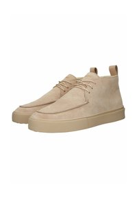 Stivaletti alla caviglia in suede beige con una texture liscia, suola in gomma piatta, punta rotonda e un design minimalista con lacci. Include un tassello posteriore per la facilitazione della calzata.