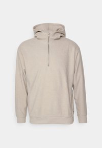 Beige hoodie met een ritskraag, lange mouwen en een zachte textuur. Beschikt over een voorste kangoeroe-pocket en ribgebreide manchetten.