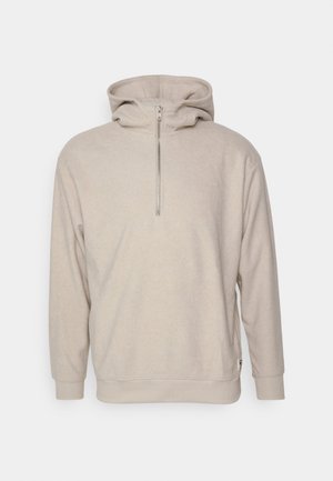 Hoodie beige con colletto zip, maniche lunghe e una texture morbida. Presenta una tasca frontale a marsupio e polsini a costine.