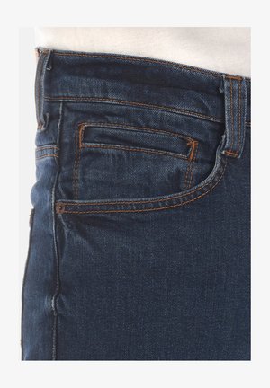 Dunkelblaue Jeans aus Denim mit hellorangefarbigen Nähten, ausgestattet mit einer Gesäßtasche und einer glatten Textur. Der obere Bereich endet in der Nähe der Taille.