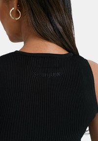 Czarny ryfrowany top na ramiączkach z okrągłym dekoltem i subtelnym logo z tyłu. Miękka tekstura z dopasowanym krojem dla szczelnego wyglądu.