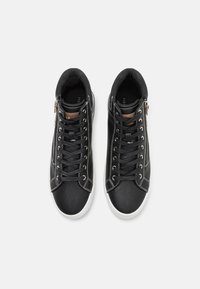 Zapatillas de baloncesto altas de cuero negro con suelas blancas, que presentan costuras en contraste, diseño de cordones y cremallera lateral con un acento marrón.