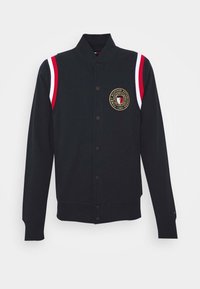 Černá varsity bunda s knoflíkovou přední stranou, stojáčkovým límcem a červenými a bílými pruhy na ramenou. Obsahuje vyšívané logo na hrudi.