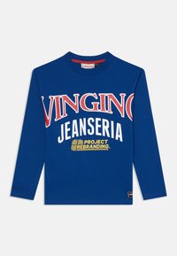 Blå langermet T-skjorte laget av bomull med rund hals. Har iøynefallende røde og hvite grafikker: "VINGINO JEANSERIA" og "PROJECT REBRANDING."