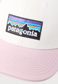 Λευκό και ροζ καπέλο με ορθογώνιο λάβαρο λογότυπο της Patagonia που απεικονίζει τη σιλουέτα βουνού και πολύχρωμες ρίγες στο μπροστινό πάνελ.
