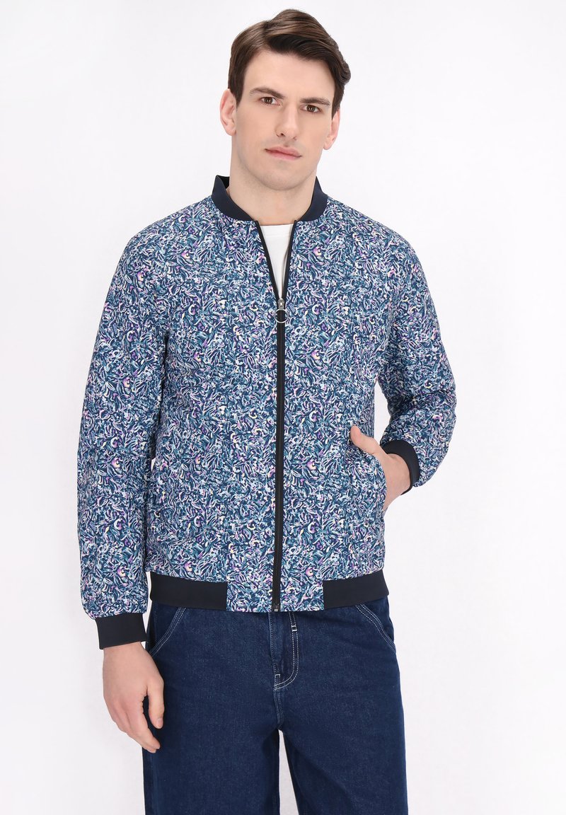 Blauwe bomberjack met een patroon, voorzien van een rits, ribgebreide manchetten en zomen, met een mix van kleuren en abstracte ontwerpelementen.