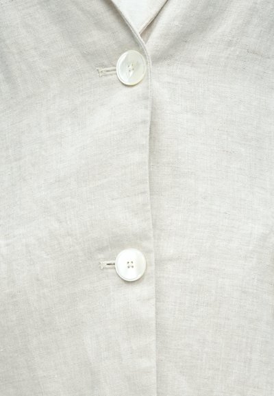Hellbeiges Leinenhemd mit einem gekerbten Kragen und einem einzelnen großen Knopf vorne, mit einer glatten Textur und einem dezenten Gewebe.