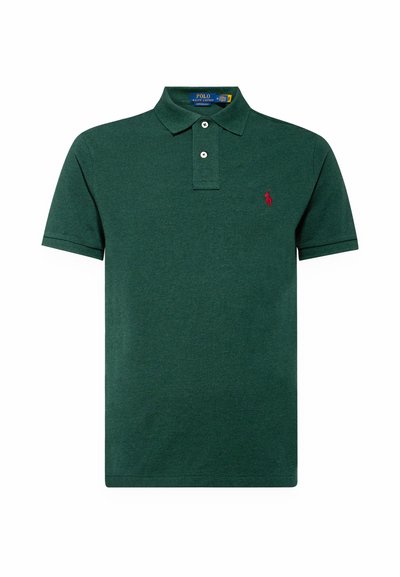 Polo-skjorte i mørkegrønn bomull med krage med to knapper og korte ermer. Har et lite rødt broderi/logo på venstre bryst.