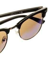 Černé sluneční brýle ve stylu kočičích očí s gradientními hnědými skly, kovovými akcenty a průhlednými nosními podložkami. Mají lesklý povrch a zakřivený design.