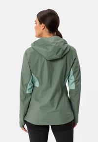 Giacca impermeabile verde con cappuccio, caratterizzata da pannelli laterali azzurri, tessuto testurizzato e design aderente. Viene mostrata la vista posteriore.