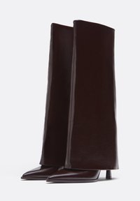Bruna läderstövlar med hög klack, med en förlängd skafthöjd, spetsiga tår och en tunn klack, med en slät yta och snygg design.
