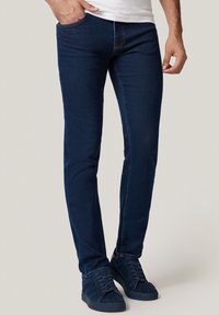 Niebieskie dżinsy w kolorze granatowym o slim fit, z kontrastującymi pomarańczowymi szwami, pięciopocketowym fasonem oraz subtelną fakturą bez przetarć.