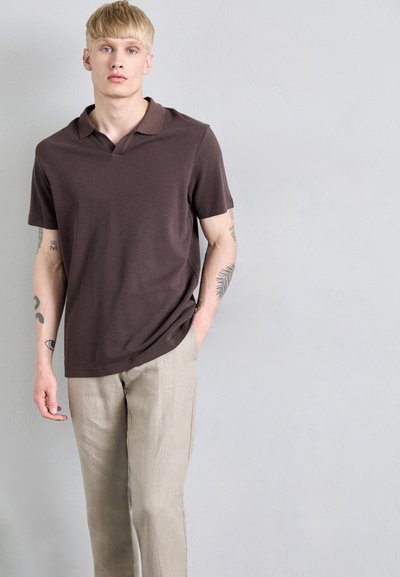 Polo-shirt marron à manches courtes avec une texture douce et un col à encoche, associé à un pantalon en lin beige clair. Design minimaliste, surface uni.