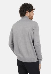 Grijze gebreide trui met een hoge kraag en geribbelde zoom. De stof is glad, met een eenvoudig ontwerp en aansluitende mouwen.