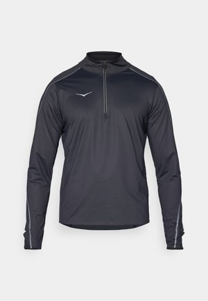 Černý dlouhý rukáv s čtvrtinovým zipem a vysokým límcem, s reflexními detaily a hladkým, lehkým materiálem.