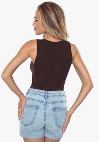 Brązowy top bez rękawów zestawiony z jasnoniebieskimi, wysokimi szortami dżinsowymi z podwiniętymi brzegami i tylnymi kieszeniami. Gładka tekstura materiału.