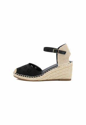 Sandalia de cuña en negro con diseño de flores recortadas, tacón a cuadros beige, detalles de yute trenzado y correa ajustable en el tobillo.