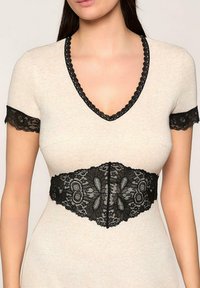 Czarna koronkowa opaska z kwiecistym wzorem i falbaniastymi brzegami; noszona na jasnobeżowym, krótkim rękawie, dekolcie w serek. Teksturowany i misterny wzór.