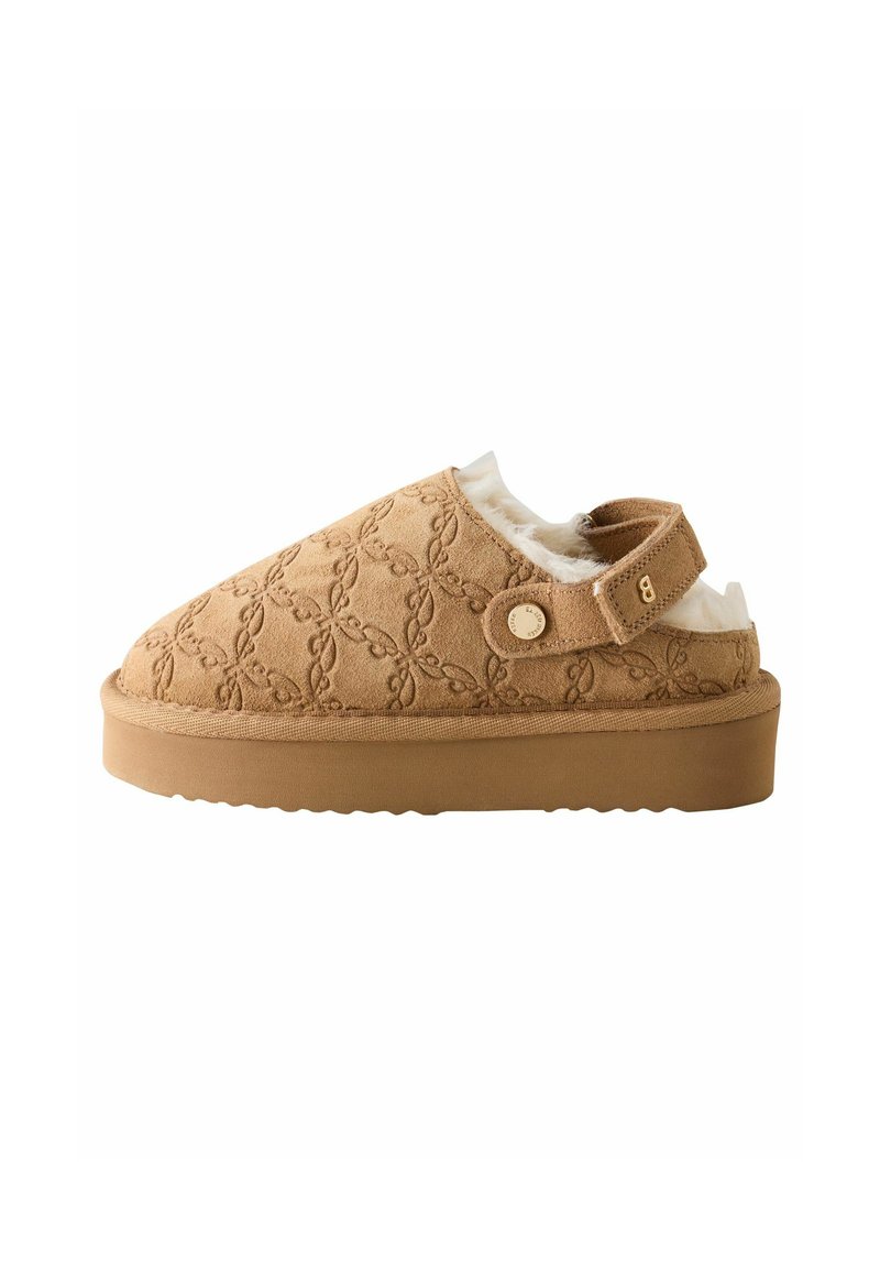 Beige Wildleder Slipper mit Verzierungen, einem gepolsterten Innenteil und einem Klettverschluss. Verfügt über eine dicke Gummisohle und ein Blumenmuster.