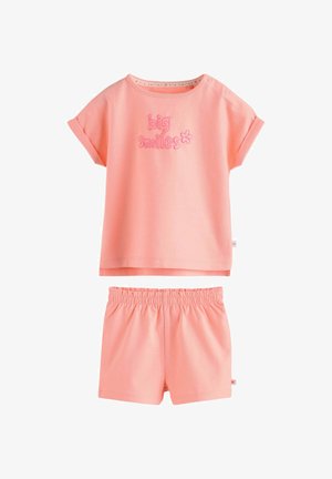 Mekana roza kratkih rukava s natpisom "veliki osmijesi" i cvijetom, uparena s odgovarajućim kratkim hlačama s elastičnim strukom za malu djecu.