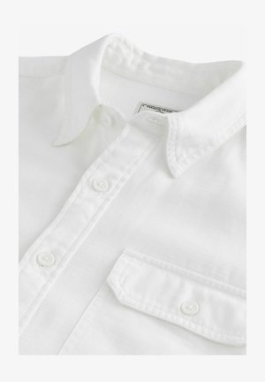 Bijela košulja s gumbima i klasičnom kragnom, jednim džepom na prsima i teksturiranom tkaninom; ima bijele gumbe i oznaku unutar kragne.