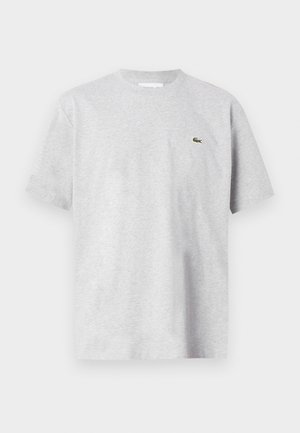 Hellgraues T-Shirt mit kurzen Ärmeln und Rundhalsausschnitt, mit einem kleinen grünen Krokodil-Logo auf der linken Brust.