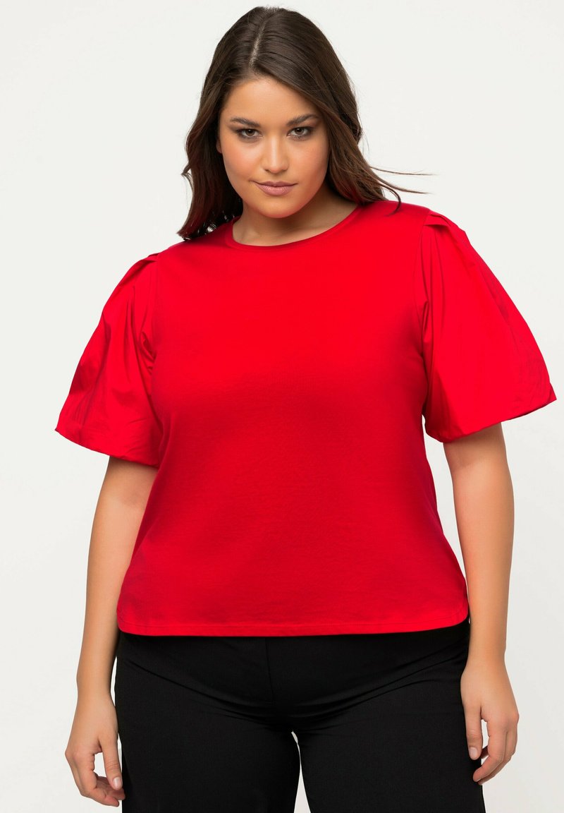 T-shirt rossa a maniche corte con maniche a sbuffo, colletto rotondo e vestibilità rilassata, realizzata in tessuto morbido e leggero.